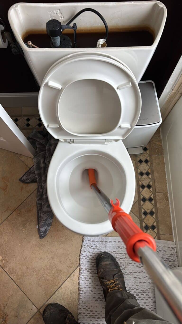 Recent Projects 1 Plumber clearing a clogged toilet with an auger in a Littleton home